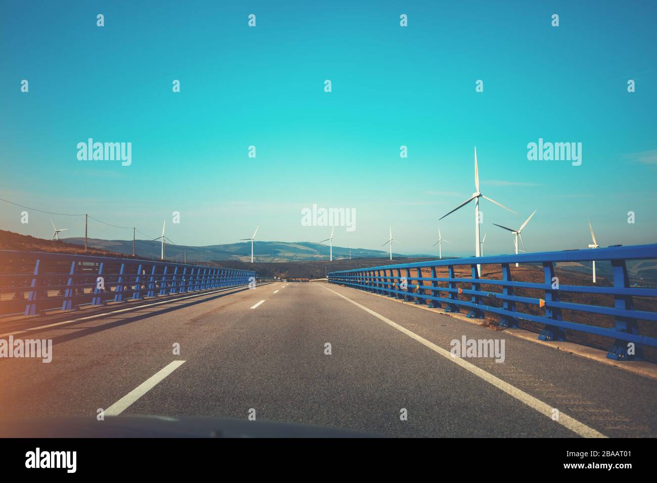 Vista del ponte sul fiume attraverso il parabrezza. Bellissimo paesaggio con autostrade, ponti e generatori di vento. Asturie, Spagna Foto Stock