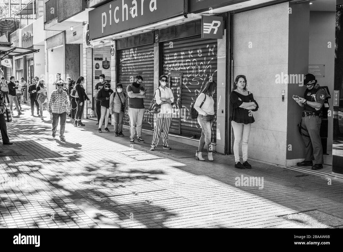 Persone che aspettano in Providencia strade per entrare all'interno delle banche e negozi durante le ultime ore prima del coprifuoco perché coronavirus malattia COVID-19 Foto Stock