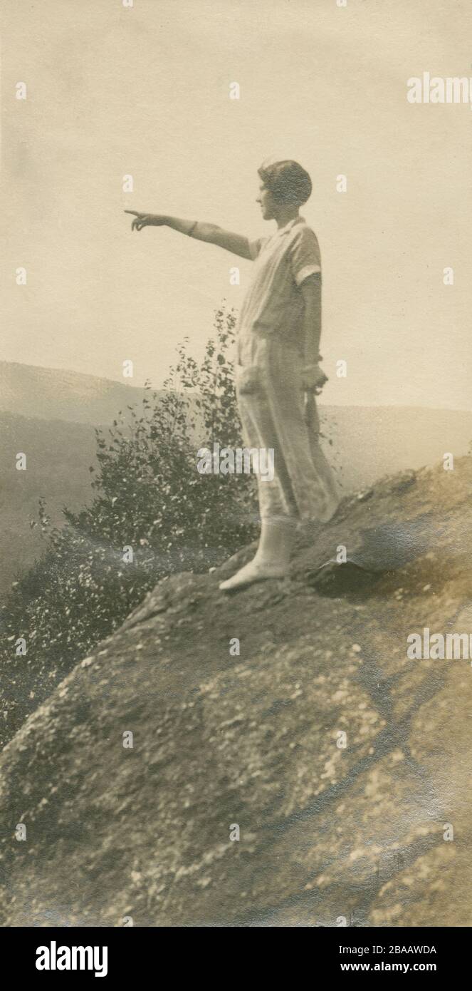 Fotografia antica del 1924, una donna punta da uno sperone roccioso. Posizione esatta sconosciuta; probabilmente Rhode Island. FONTE: FOTOGRAFIA ORIGINALE Foto Stock