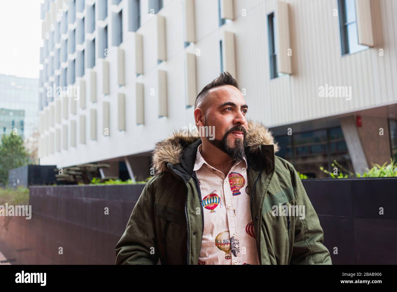 Uomo barbuto in piedi e rilassarsi sulle scale contro l'edificio degli uffici Foto Stock