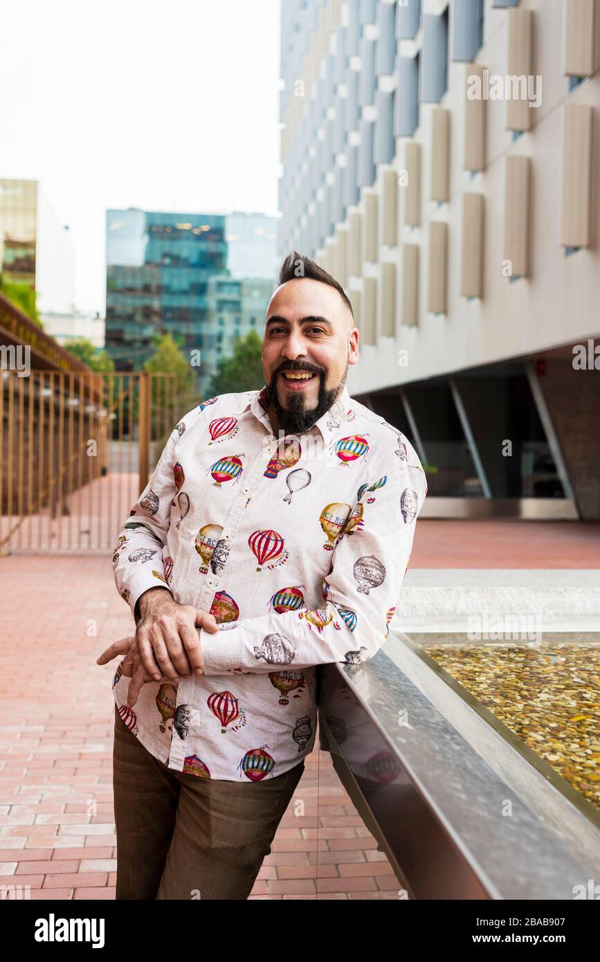 Uomo barbuto in piedi e rilassarsi sulle scale contro l'edificio degli uffici Foto Stock