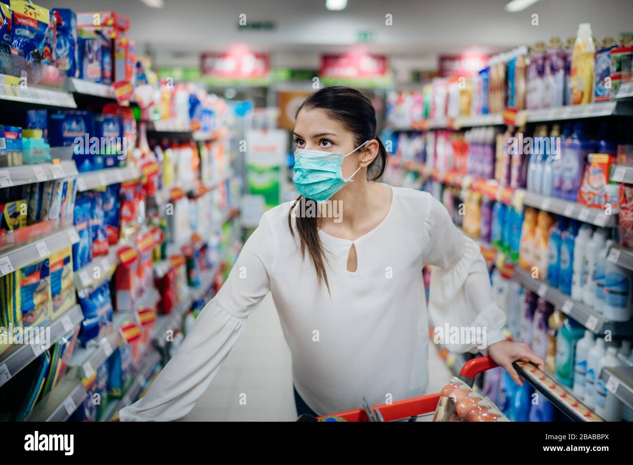 Donna che indossa maschera protettiva per la preparazione di virus pandemic spargere quarantena.trovare i prodotti giusti sugli scaffali nel supermercato.igiene Foto Stock