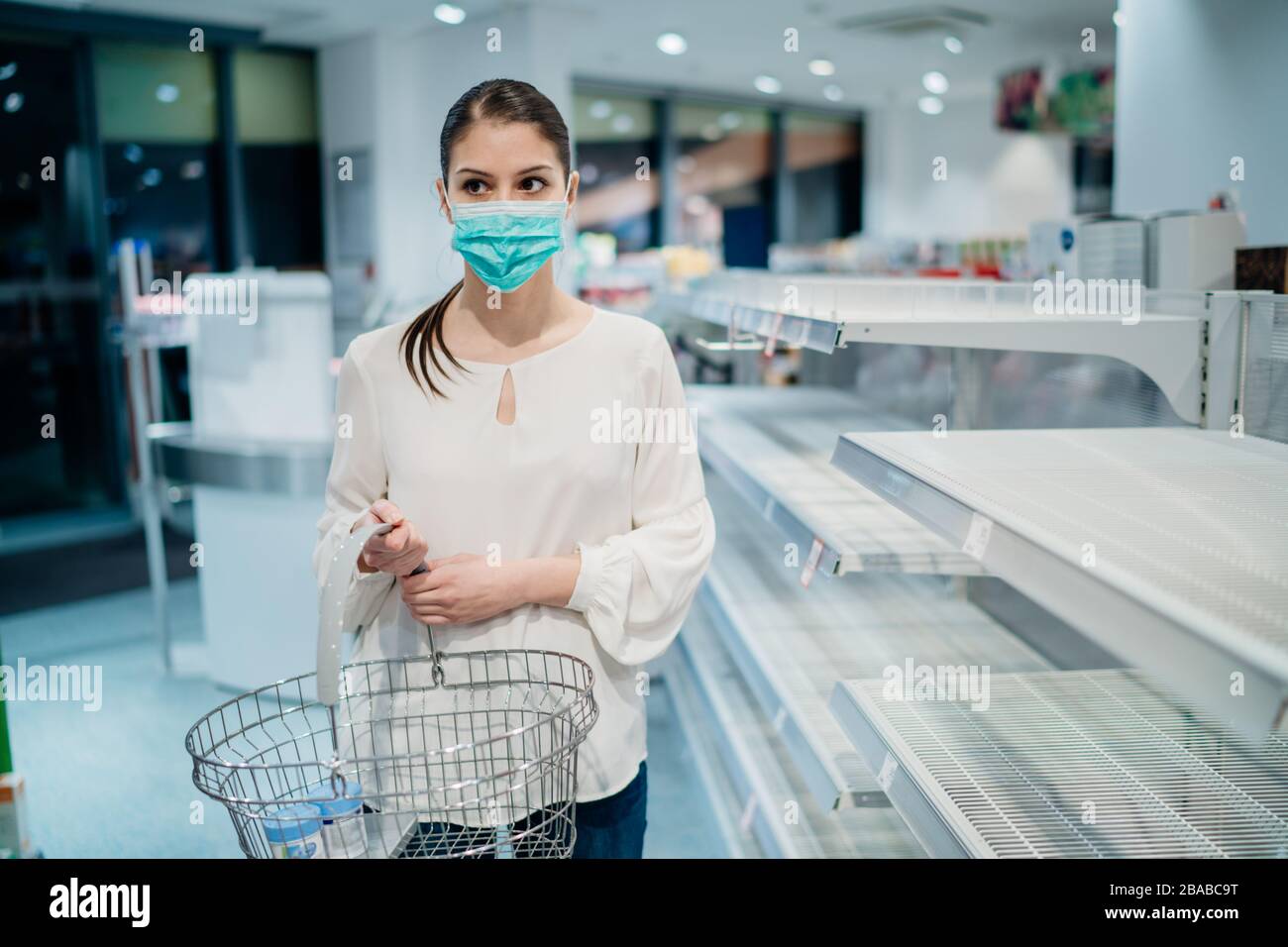 Donna che indossa maschera di acquisto in supermercato/farmacia con esaurito supplies.empty scaffali nel supermercato a causa di nuovo coronavirus covid-1 Foto Stock