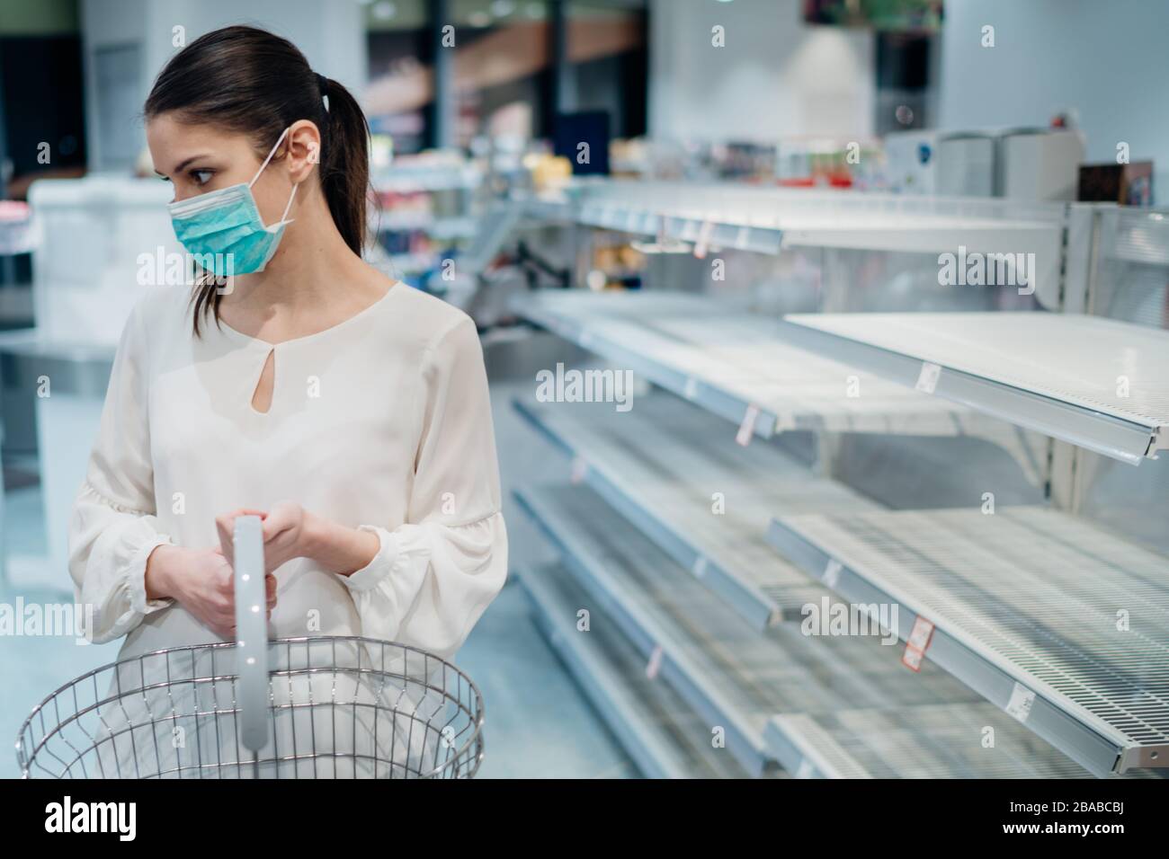 Donna che indossa maschera di acquisto in supermercato/farmacia con esaurito supplies.Shopper panico di acquisto e di ostaggio che conduce al mercato insostenibile.W. Foto Stock