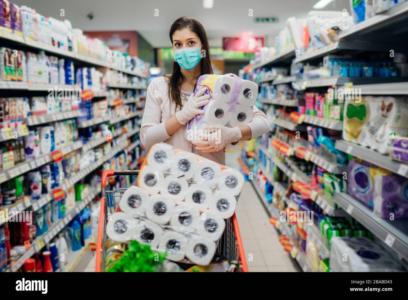 Donna shopper con maschera e guanti panico acquisto e carta da bagno in fornitura store.Preparing per il virus patogeno pandemic quarantena.Prepper b Foto Stock