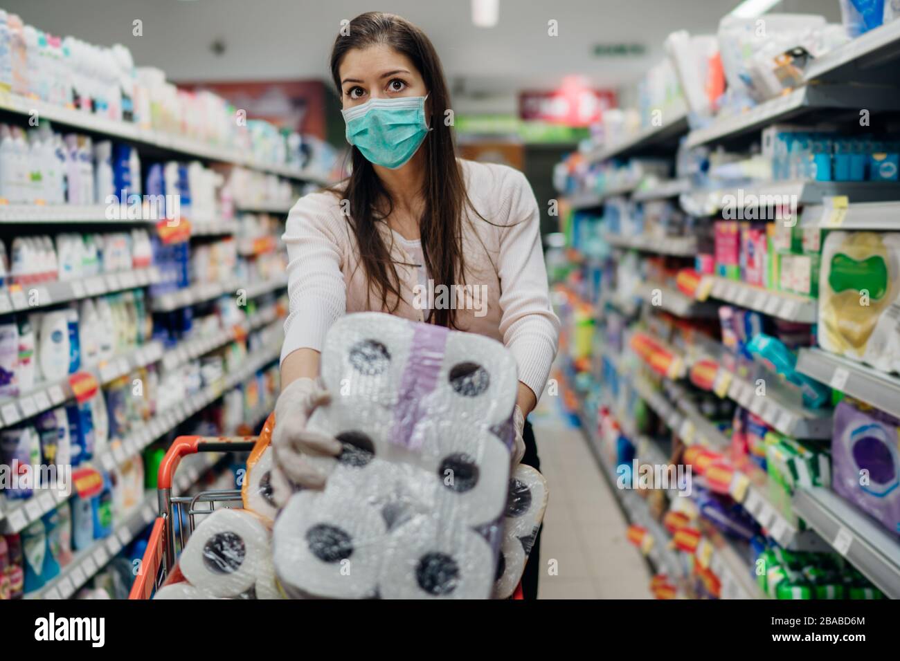 Donna shopper con maschera e guanti panico acquisto e carta da bagno hoarding in supply store.Preparing per patogeno virus pandemic quarantena.Prepper Foto Stock