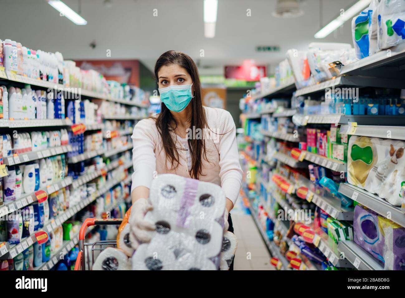 Donna shopper con maschera e guanti panico acquisto e carta da bagno in fornitura store.Preparing per il virus patogeno pandemic quarantena.Prepper b Foto Stock
