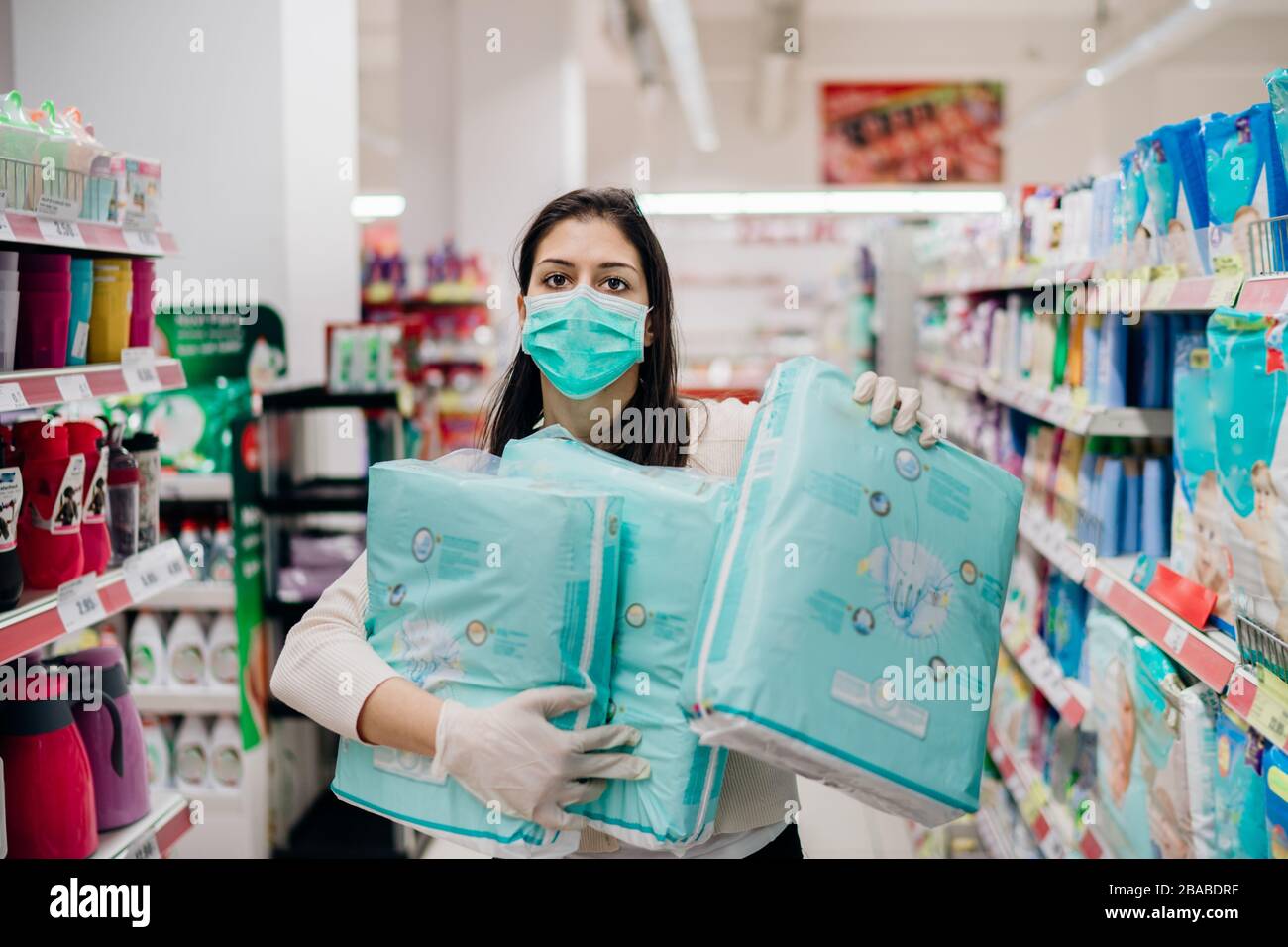 Donna shopper con maschera e guanti panico acquisto e hoarding monouso diapers.Preparing per il virus patogeno pandemic quarantena.Prepper acquisto bulk b Foto Stock