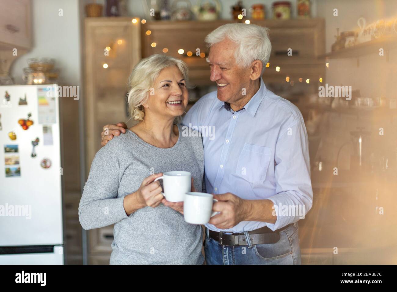 Felice coppia senior abbracciando nella loro casa Foto Stock
