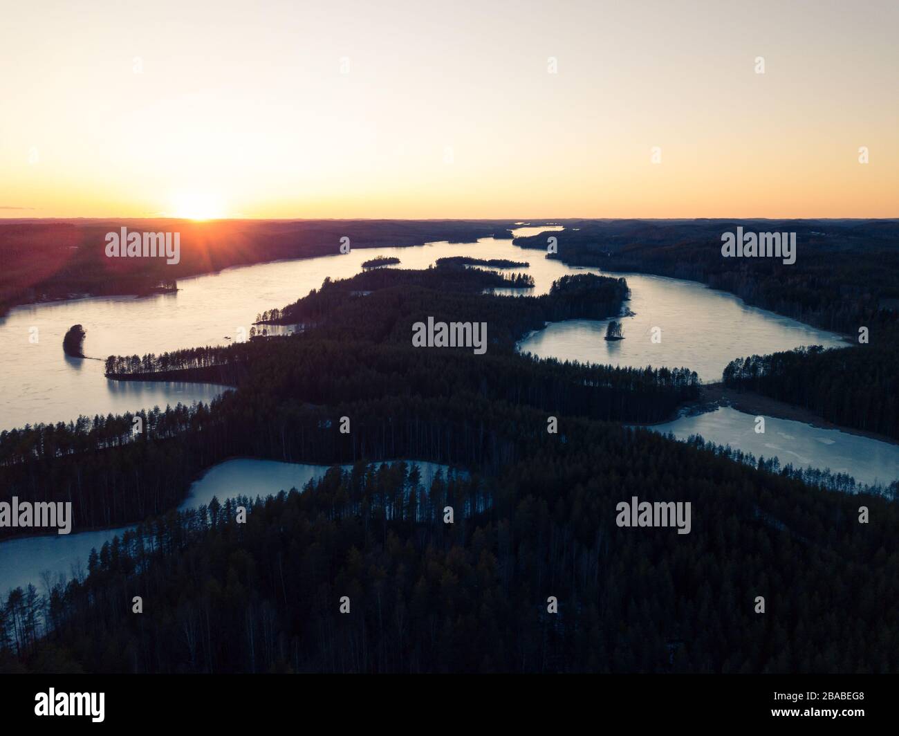 Tramonto primaverile dietro lago ghiacciato Foto Stock