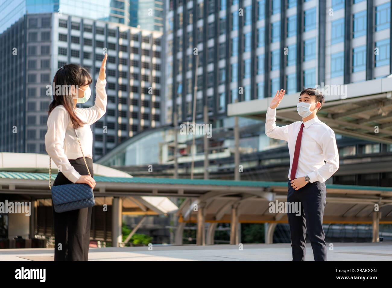 Uomo e donna d'affari asiatici salutano e salutano con un collega d'affari e indossano una maschera a distanza di 1 metro proteggere dal COVID-19 Foto Stock