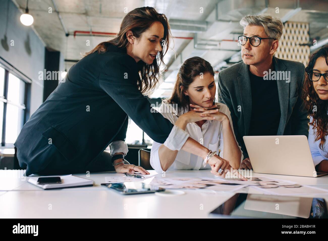 Designer che dà alcune nuove idee sul progetto al suo team in riunione. Persone aziendali che parlano di un nuovo progetto aziendale in ufficio. Foto Stock