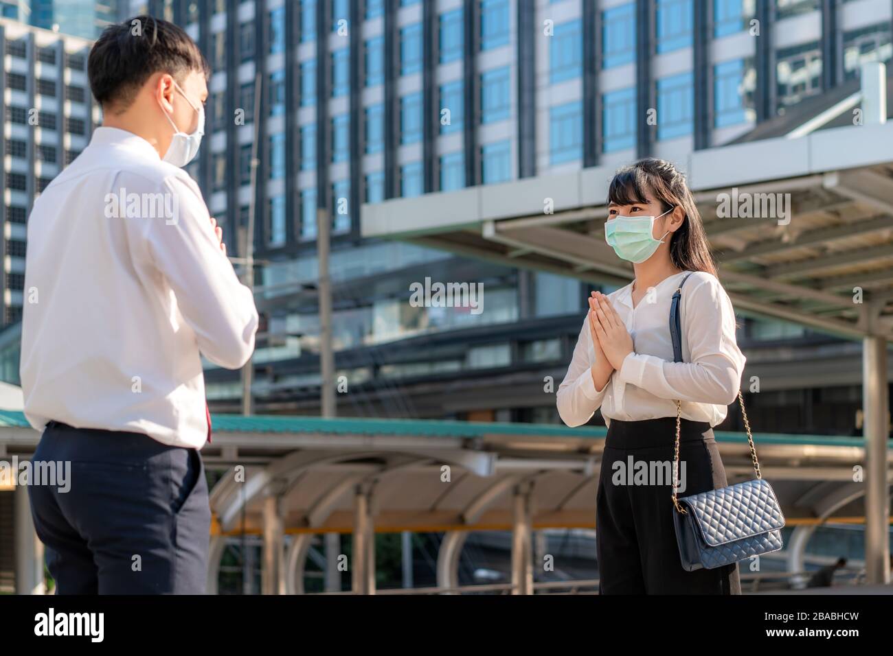 Il rispetto di paga è nuovo saluto del romanzo per evitare la diffusione del coronavirus. Due giovani uomini d'affari asiatici e uomini d'affari amici si incontrano in font di bui ufficio Foto Stock