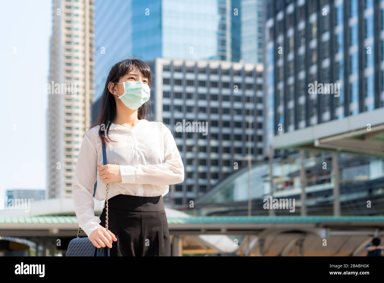 Giovane stress donna d'affari asiatica in camicia bianca andare a lavorare in città inquinamento indossa maschera di protezione prevenire la polvere PM2,5, smog, inquinamento dell'aria e. Foto Stock