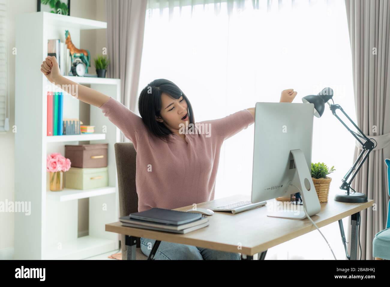 Asian business donna lavoro da casa e allungare il suo corpo perché sentirsi stanco e sonnolento di lavoro sul computer, intelligente donna che lavora a casa. Vita Foto Stock
