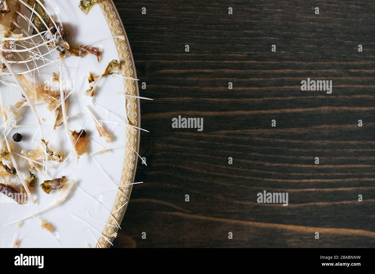 Pesce ossa su un unico piatto bianco. Sfondo del tavolo in legno con spazio copia Foto Stock