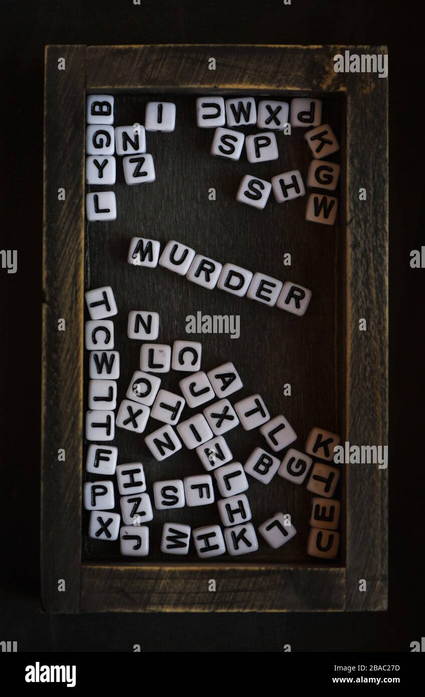 Ancora vita mostrando nero e bianco blocchi di lettere spell out la parola omicidio tra le altre lettere all'interno di una scatola di legno dipinto nero. Foto Stock