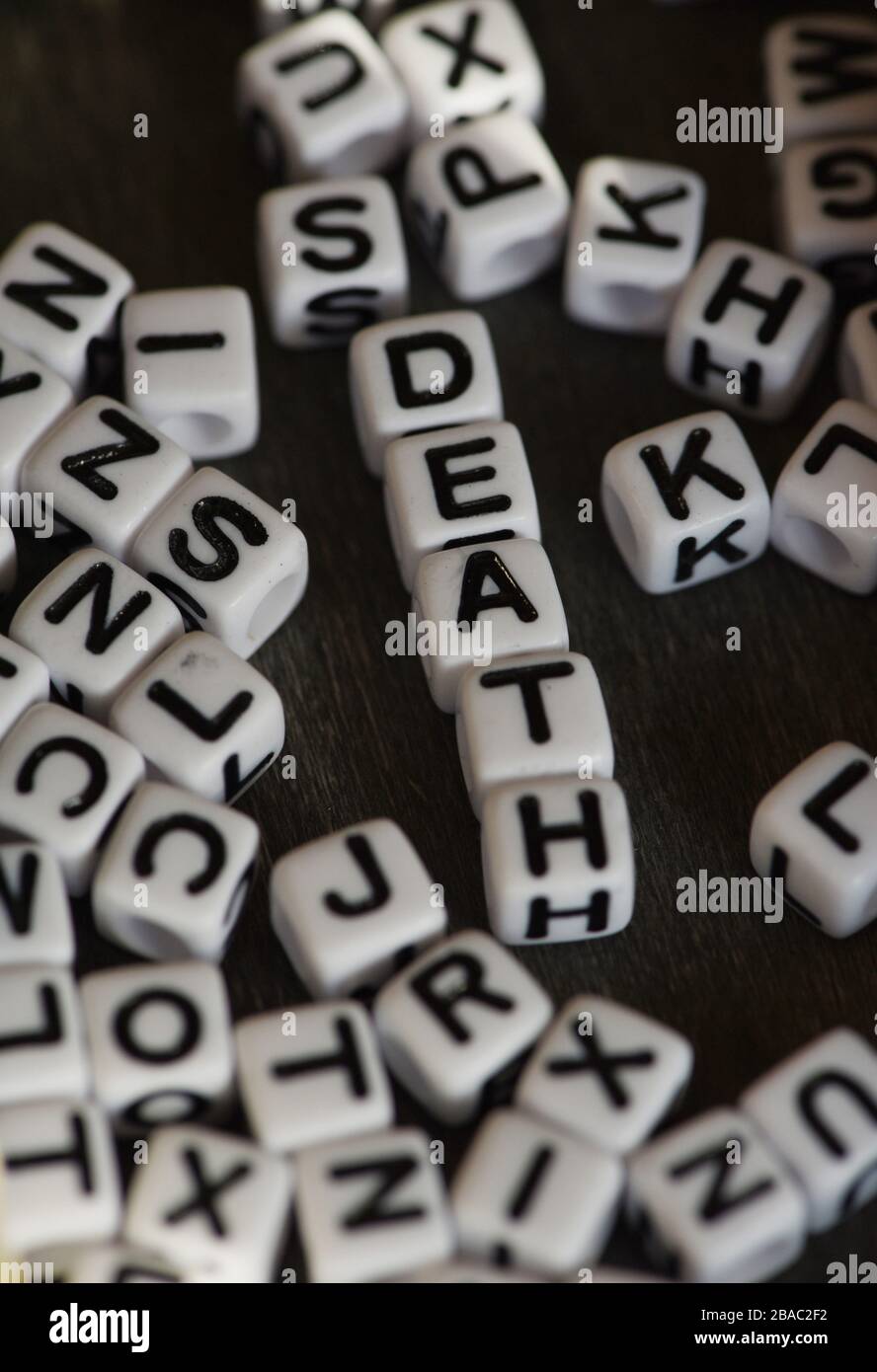 Ancora la vita che mostra blocchi di lettera in bianco e nero che ortografano la morte di parola fra altri blocchi di lettera contro uno sfondo nero Foto Stock