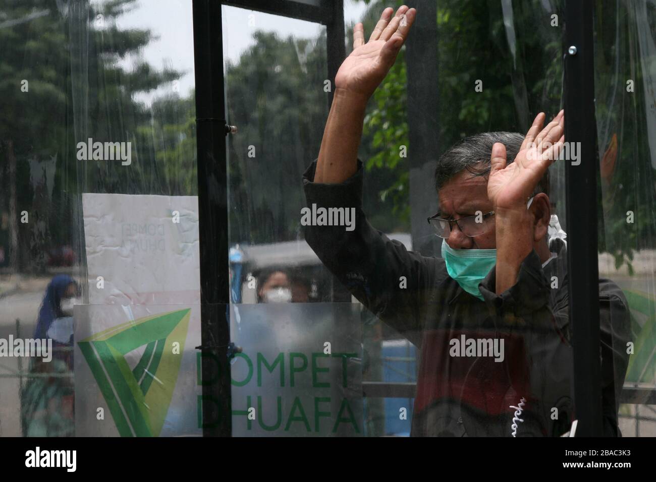 Giacarta, Indonesia. 25 Marzo 2020. I residenti che saranno attivi in luoghi pubblici, utilizzano la camera di disinfezione di Blok M, Giacarta Sud, Indonesia. In questa camera di sterilizzazione tutto il corpo della persona verrà spruzzato con liquido disinfettante. Questo liquido disinfettante ha la funzione di uccidere il virus della corona che si attacca ai vestiti o al corpo della persona, per anticipare la diffusione del virus della corona (COVID-19) negli spazi pubblici. (Foto di Kuncoro Widyo Rumpoko/Pacific Press) Credit: Pacific Press Agency/Alamy Live News Foto Stock