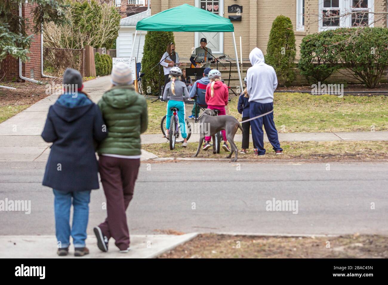 Grosse Pointe Park, Michigan, Stati Uniti. 26 marzo 2020. Nolan Eszes, 14 anni, e le sue sorelle Hadley, 11 anni, e Sidney, 6 anni, suonano un concerto di portico per i loro vicini. Hanno suonato un concerto ogni sera da quando il governatore del Michigan Gretchen Whitmer ha ordinato ai residenti di "fare il loro aiuto" a causa della pandemia del coronavirus. Credit: Jim West/Alamy Live News Foto Stock