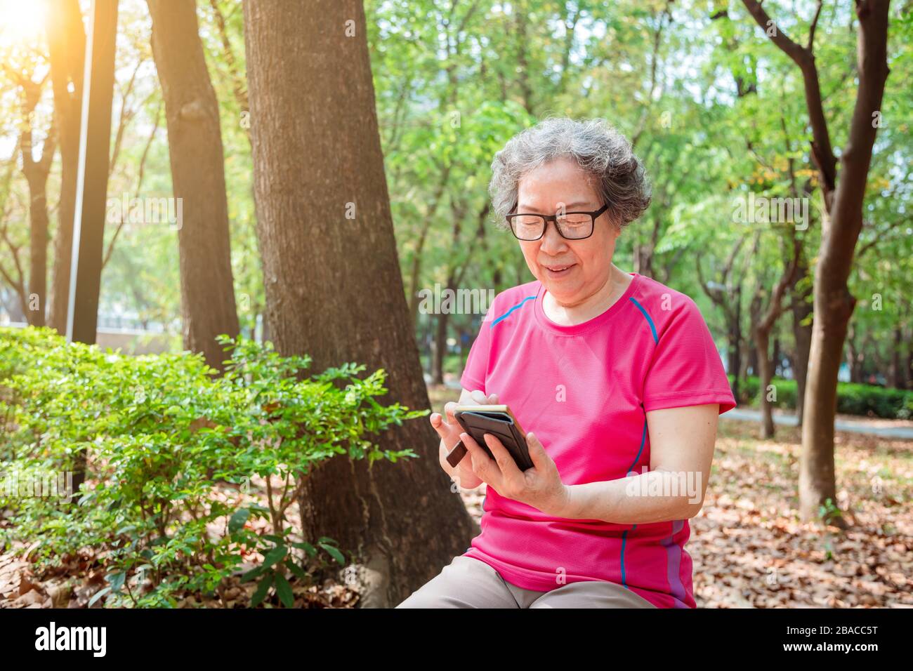 donna anziana asiatica in occhiali e la lettura del telefono cellulare Foto Stock