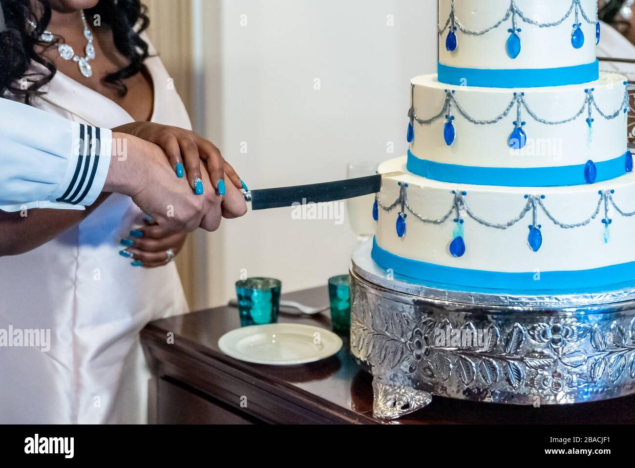 Sposa e uno sposo che taglia la bella torta bianca di nozze - concetto di matrimonio interrazziale Foto Stock