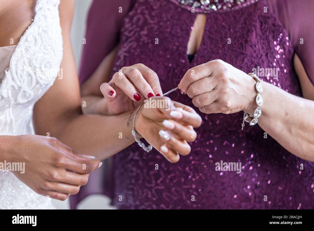La madre della sposa che la aiuta a indossare gioielli da sposa Foto Stock