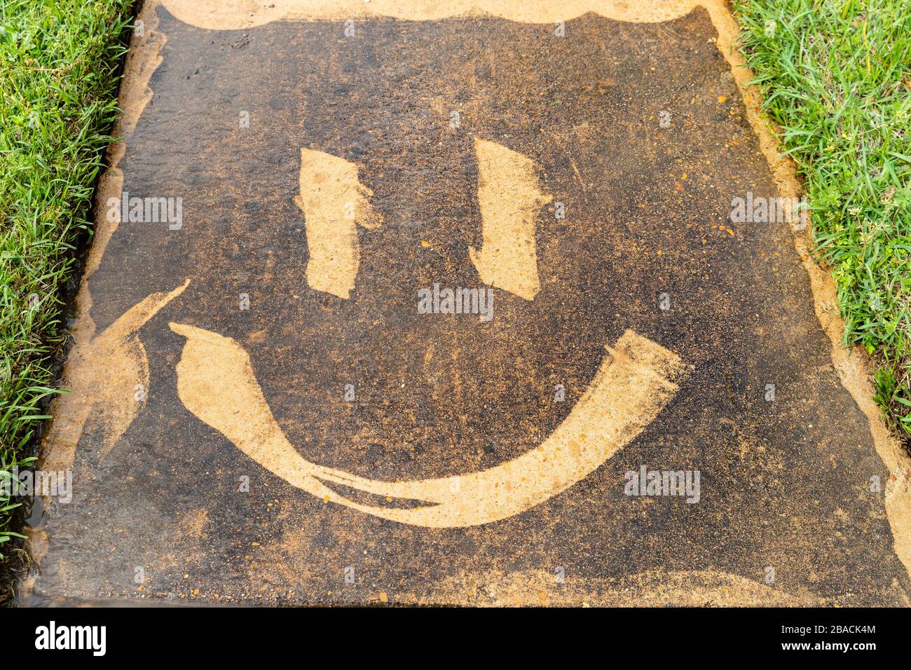 Una faccia smiley creata su un marciapiede sporco con un pulitrice a pressione Foto Stock