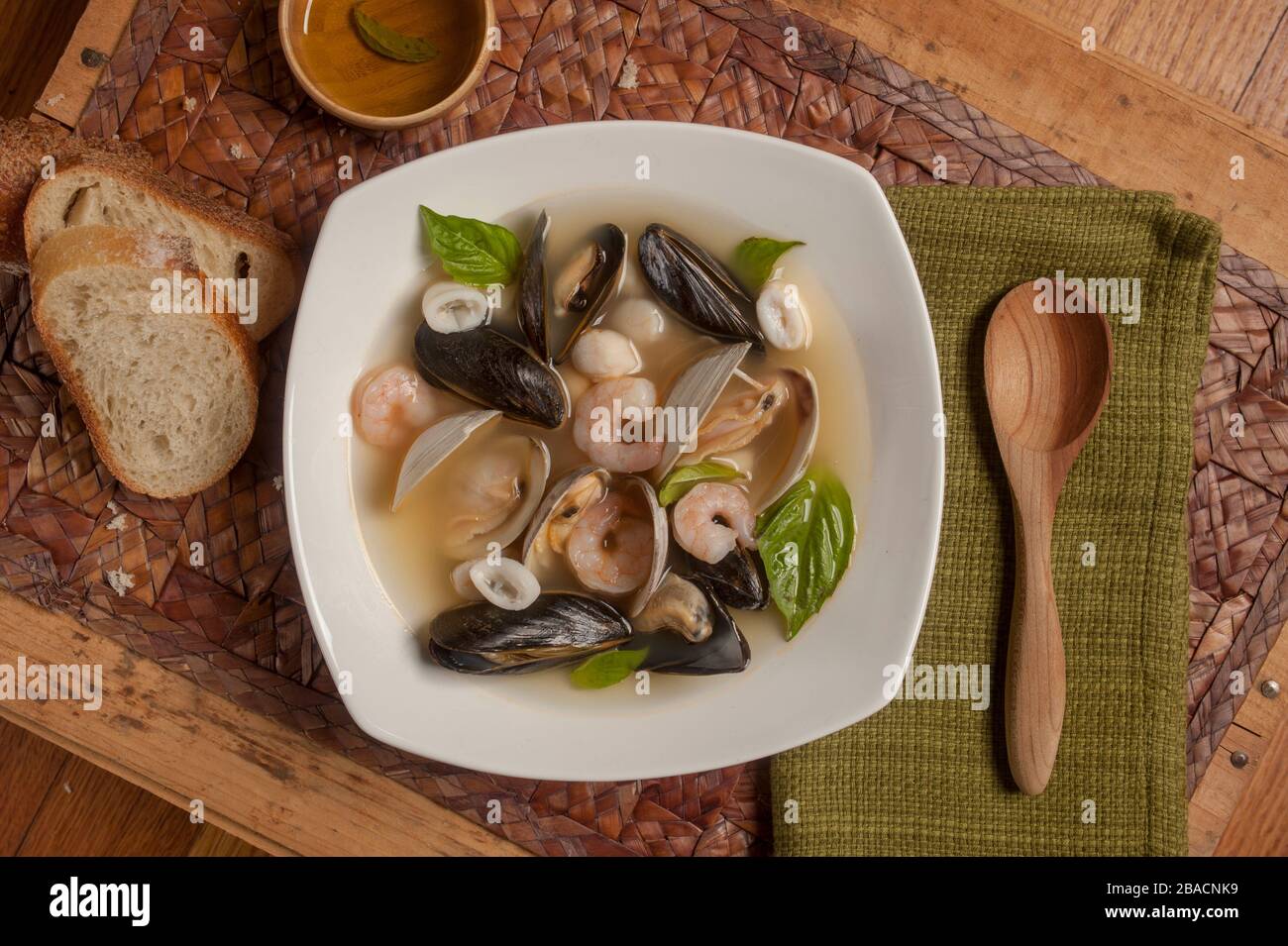 Stufato di pesce, simile al bouillabaisse, con varietà di pesce, tra cui vongole, cozze, gamberi, calamari a base di pesce guarnito con basilico Foto Stock