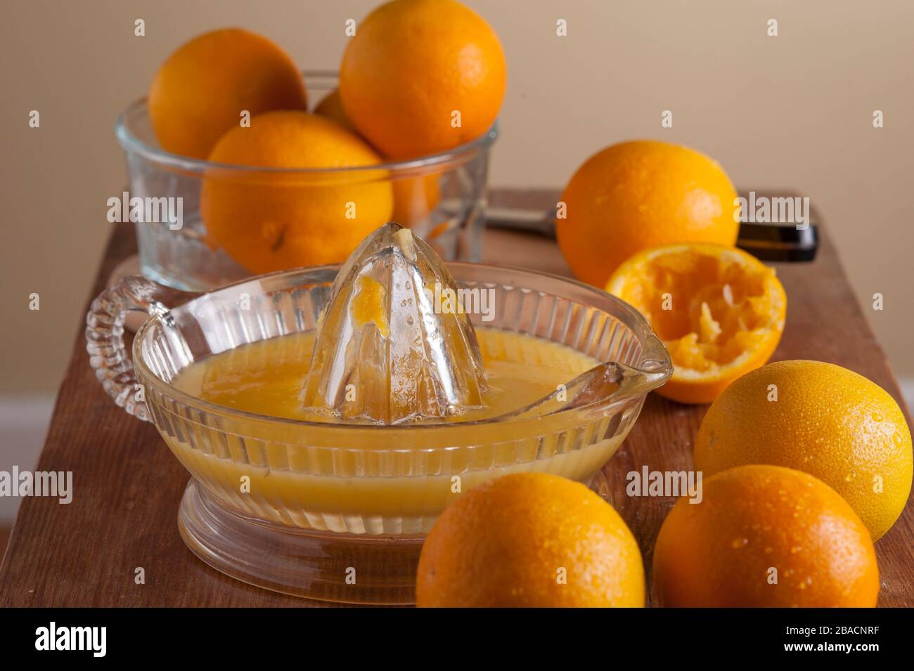 Preparazione di spremuta d'arancia fresca, arance su tagliere con alesatore di succo. Foto Stock