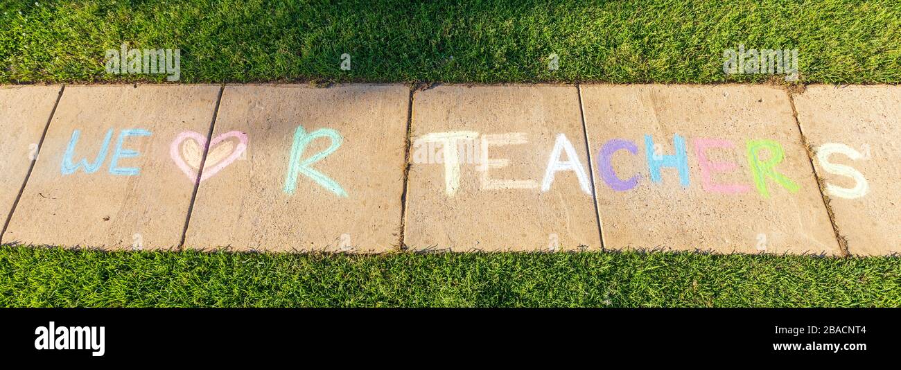 Le parole 'We Love our Teachers' scritto con il gesso marciapiede, su sfondo di pavimentazione in cemento grigio. Foto Stock