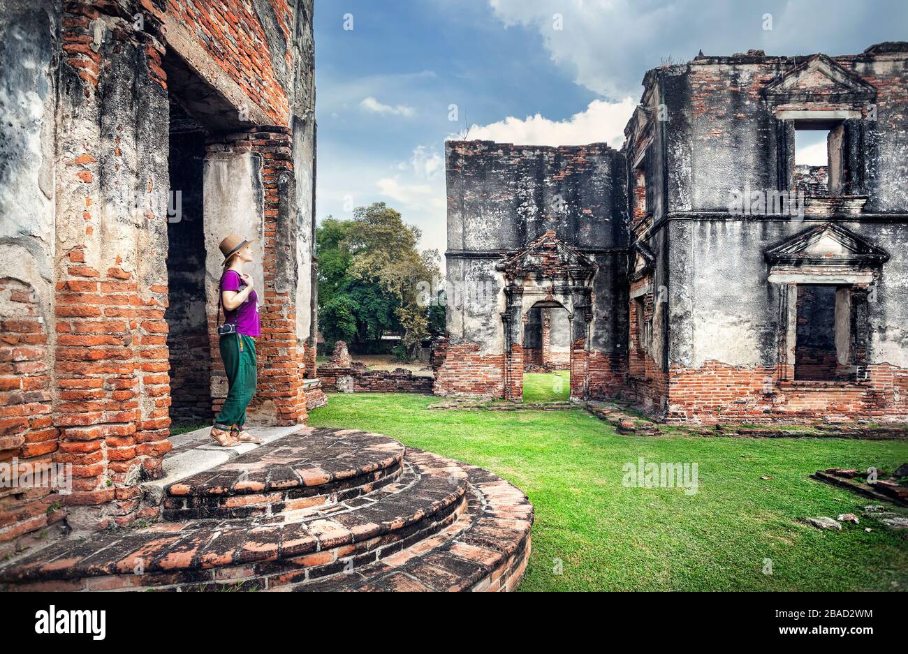 Donna turista con fotocamera foto guardando antichi rovinato Tempio della città di Lopburi, Thailandia Foto Stock