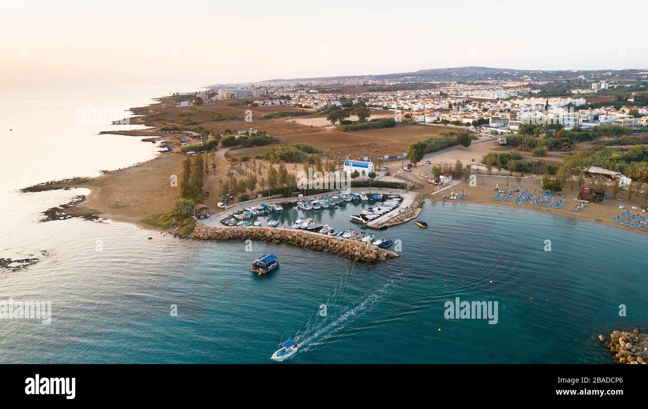 Vista aerea del tramonto sulla costa e della cappella dipinta di bianco sulla spiaggia di Agia Triada, Protaras, Famagosta, Cipro dall'alto. Vista dall'alto del tour Foto Stock