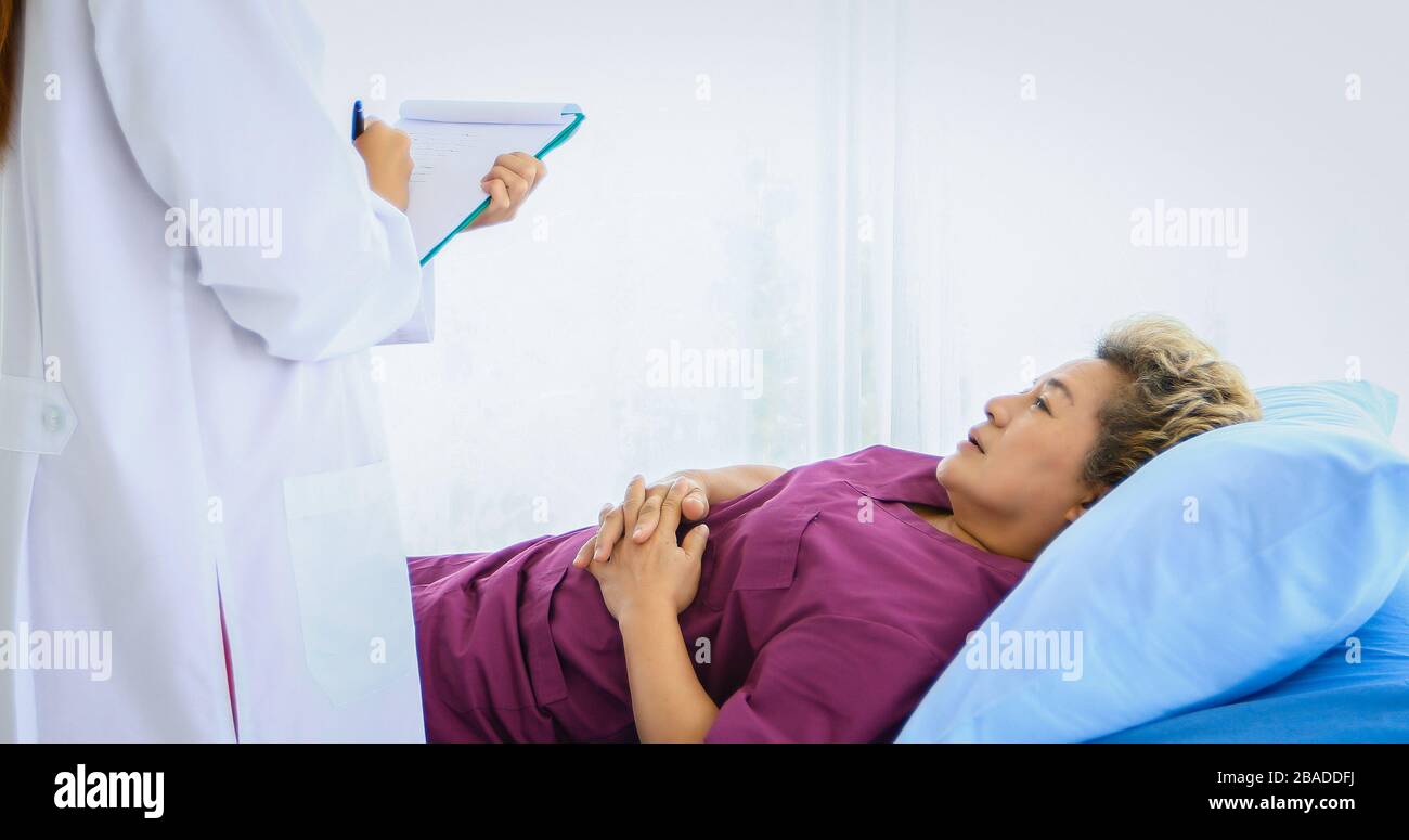 Il medico incontra e spiega il farmaco al paziente di vecchia donna sdraiato a letto presso gli ospedali Foto Stock