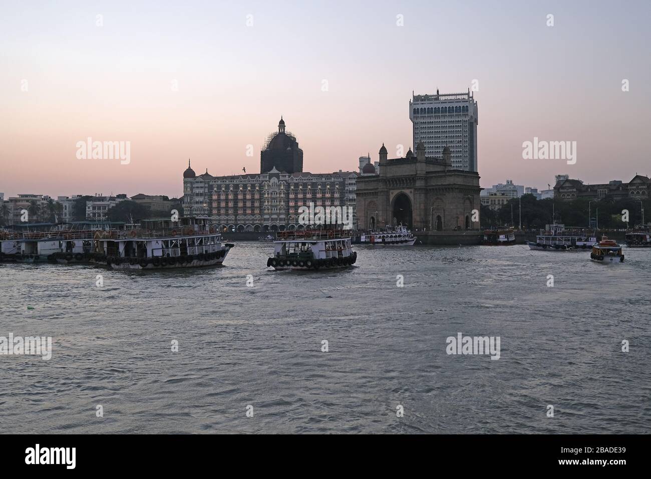 Taj Mahal Hotel, Gateway of India e barche turistiche in acqua del Mar Arabico al tramonto a Mumbai, India Foto Stock