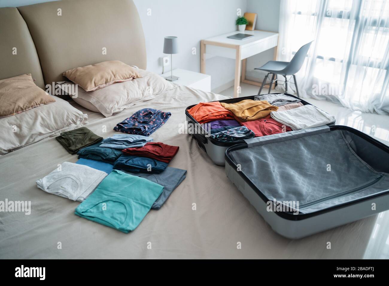 apri la valigia con un sacco di vestiti sul letto in camera da letto Foto  stock - Alamy
