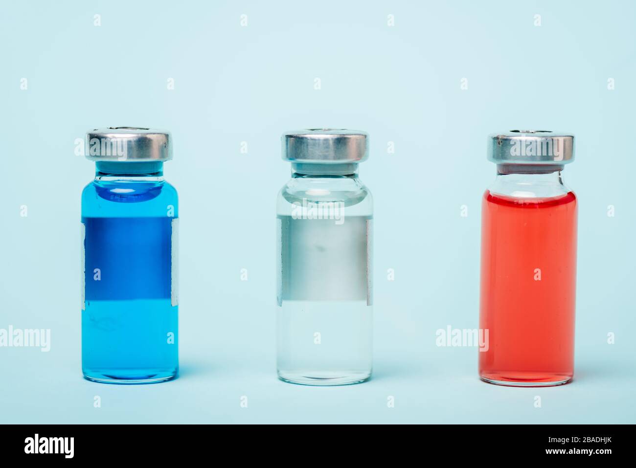Vista ravvicinata dei vasi colorati con farmaci ormonali sulla superficie blu Foto Stock