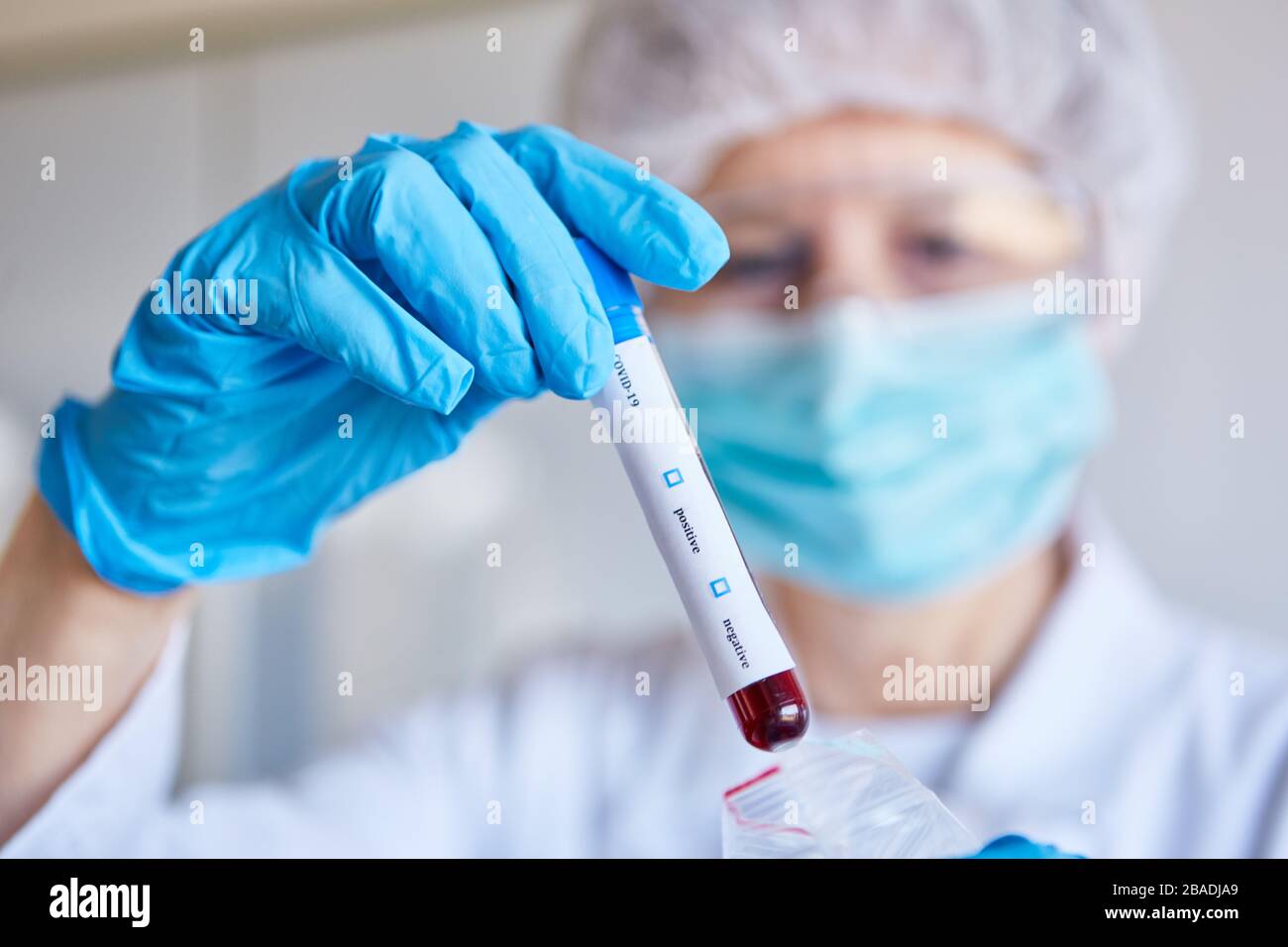 La mano contiene il campione di sangue per il test del coronavirus Covid-19 in laboratorio Foto Stock