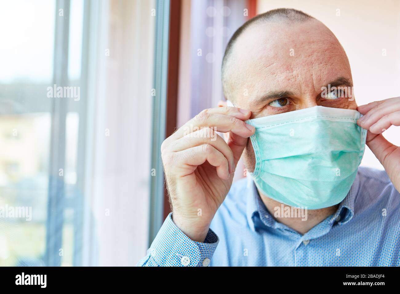 Uomo ansioso con maschera facciale in quarantena durante l'epidemia di coronavirus Covid-19 Foto Stock