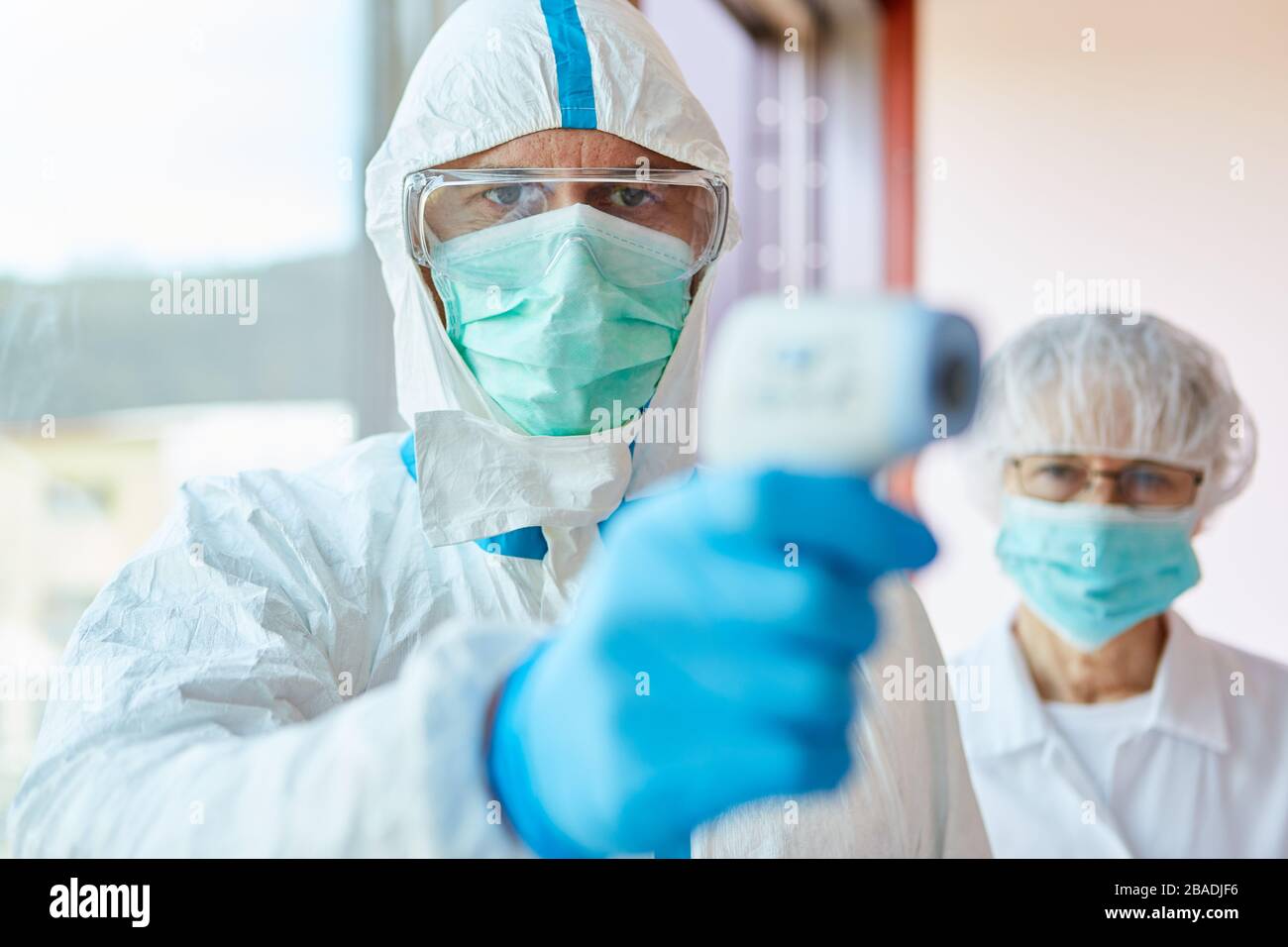Professionisti medici in indumenti protettivi che misurano la febbre senza contatto al centro di test Covid-19 durante l'epidemia di coronavirus Foto Stock