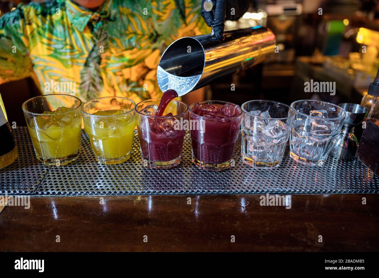 Barman che versa cocktail di frutta in vetro con ghiaccio sul bancone bar in discoteca Foto Stock