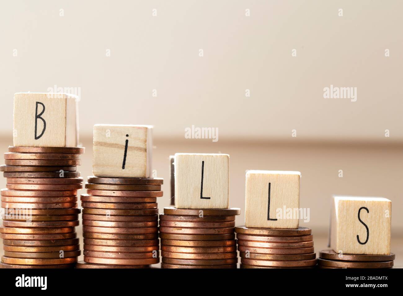 Blocchi di legno con la parola bollette e mucchio di monete, soldi scalini pagamento delle tasse e del debito allo Stato. Concetto di crisi finanziaria e. Foto Stock