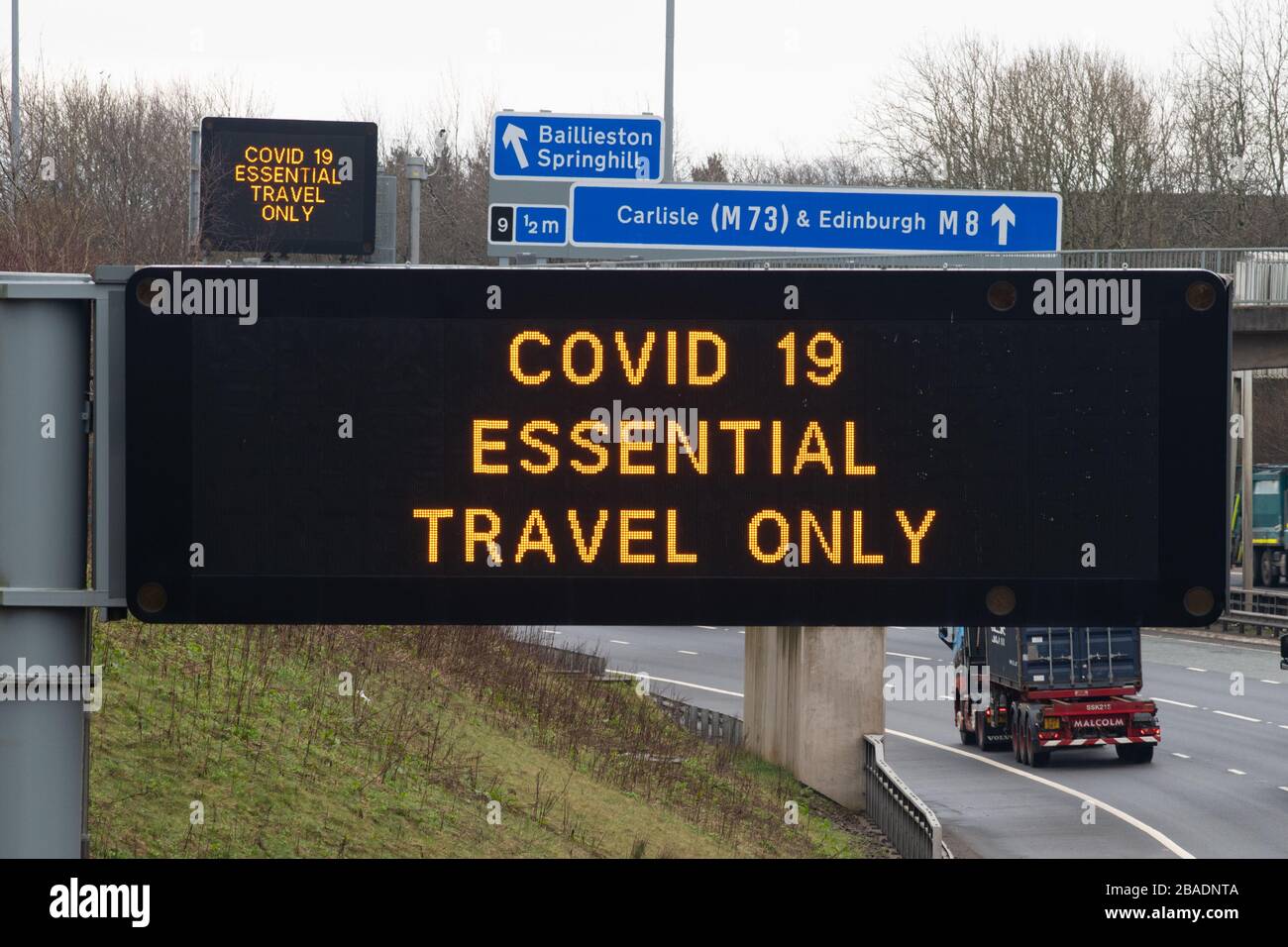 Cartello segnaletico Covid 19 Essential Travel solo su autostrada M8, Glasgow, Scozia, Regno Unito Foto Stock