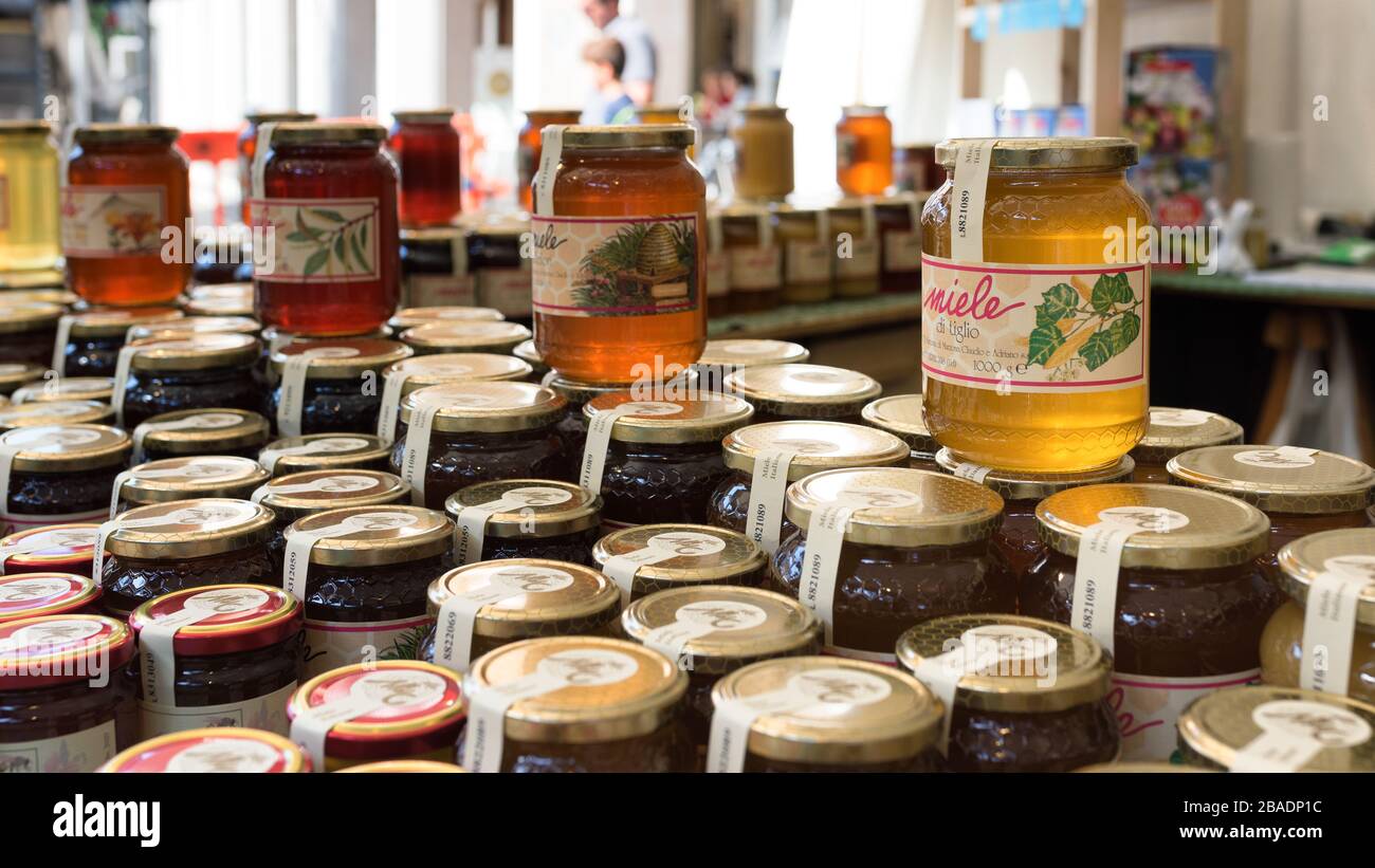 Vasi di miele di diverse fonti floreali, che indicano differenze di colore e consistenza per la vendita in un mercato italiano all'aperto. Foto Stock