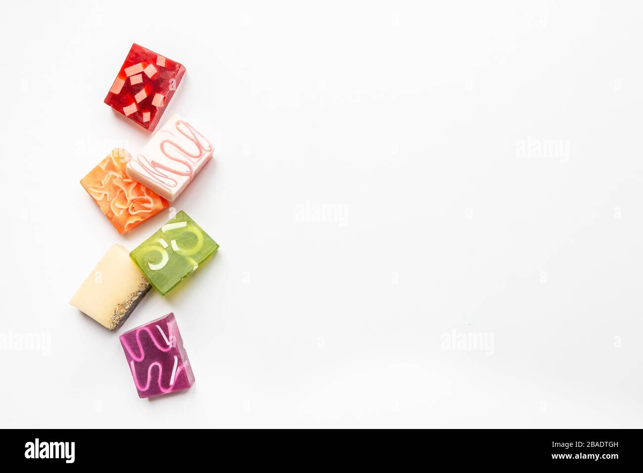 Vista dall'alto di vari saponi colorati fatti a mano. Salute organica e protezione. Spazio di copia, sfondo bianco. Foto Stock
