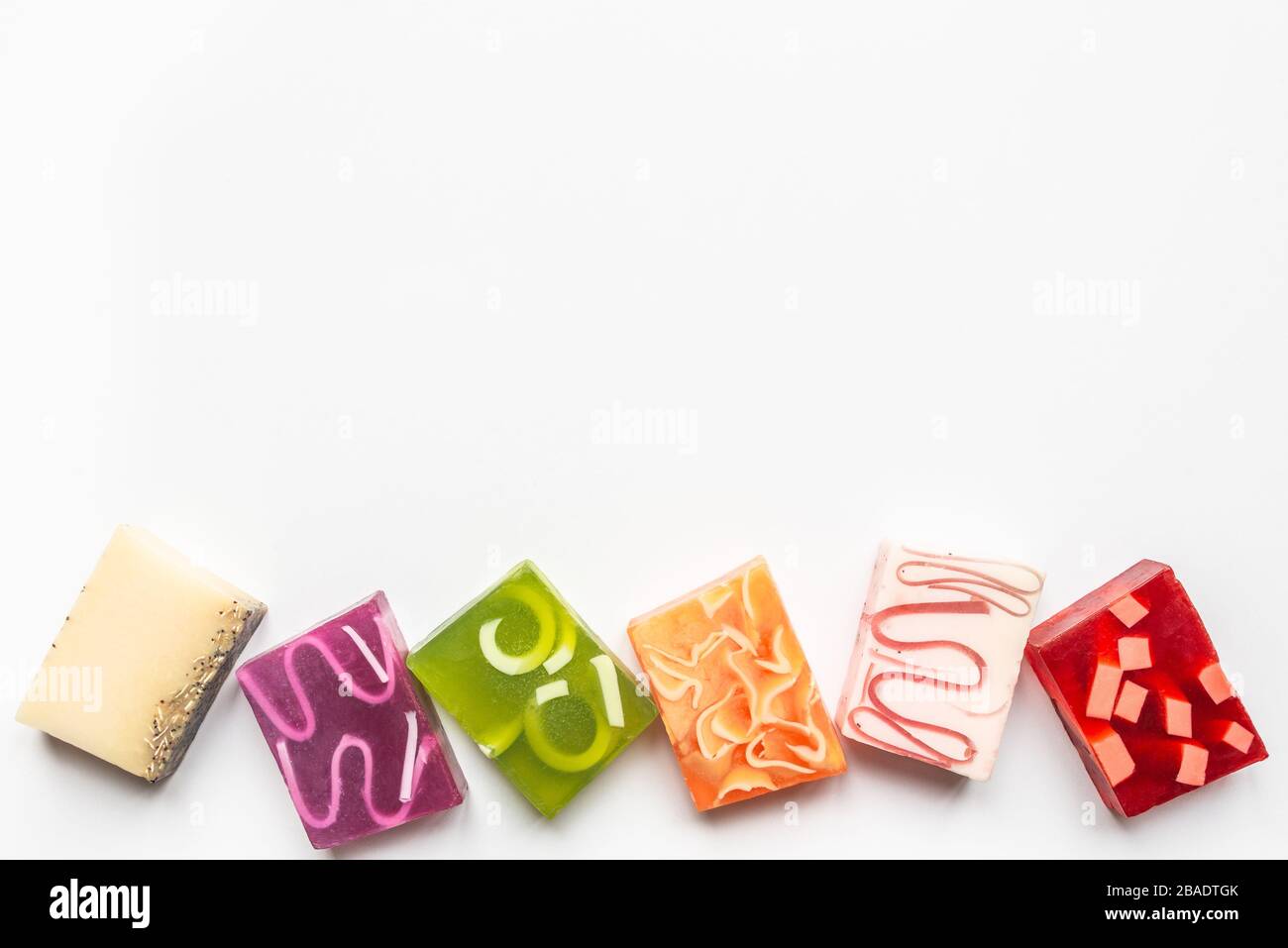 Vista dall'alto di vari saponi colorati fatti a mano. Salute organica e protezione. Spazio di copia, sfondo bianco. Foto Stock