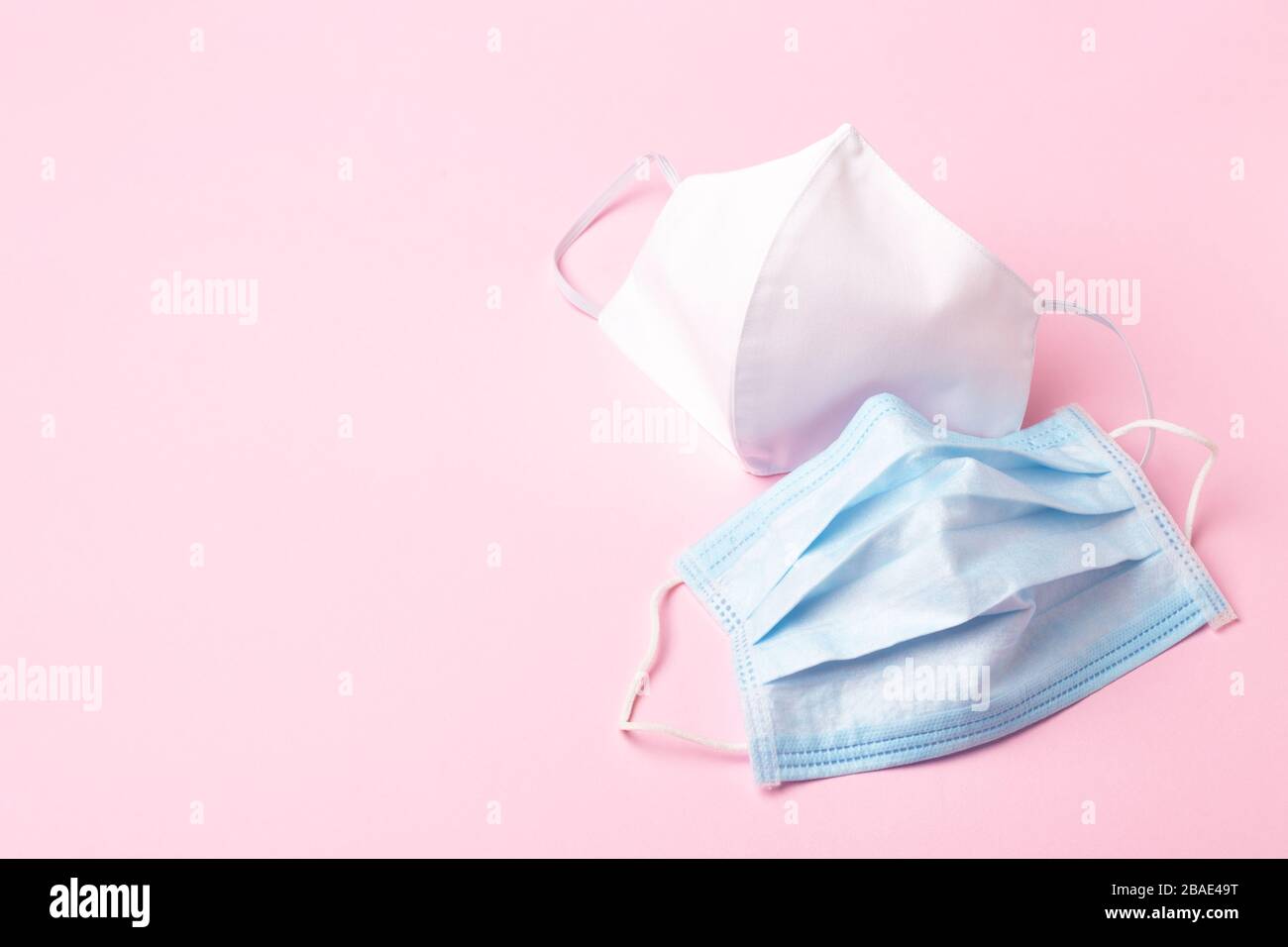 Maschera medica blu e faccia bianca fatta a mano su sfondo rosa. Protezione contro i virus. Foto Stock