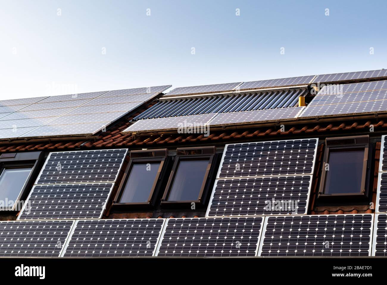 Casa con pannelli solari e pannelli solari per il riscaldamento dell'acqua sul tetto. Foto Stock