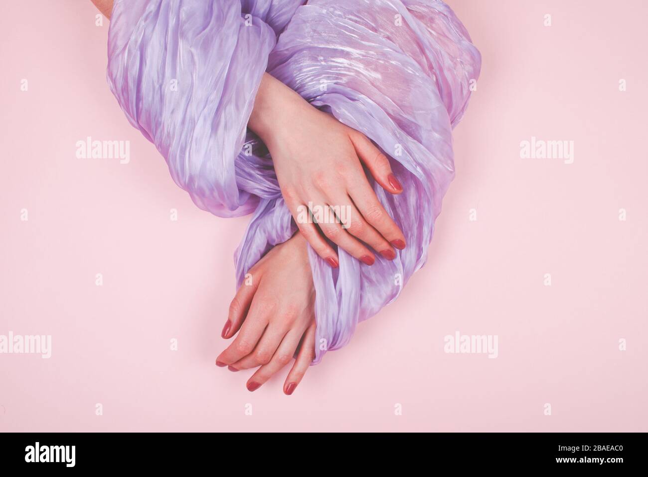 Donna mani con manicure in tessuto satinato scivolano su sfondo rosa Foto Stock