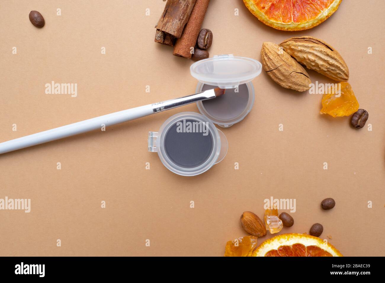 Cosmetici per il trucco naturale, prodotti per il trucco Eyebrow. Sfondo caldo con frutta secca e caffè. Foto Stock